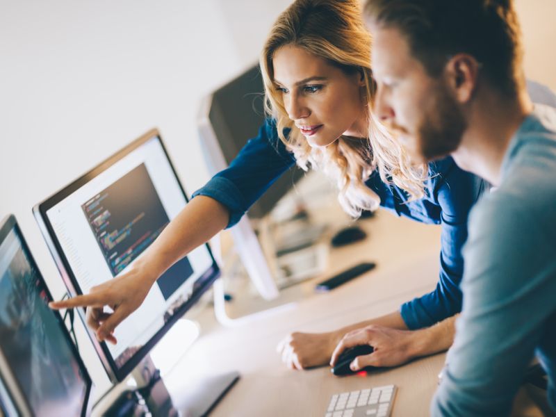 Foto: Teilnehmerinnen und Teilnehmer arbeiten gemeinsam am Computer an KI-Projekten