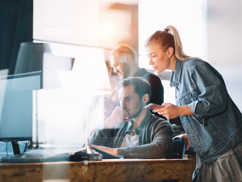 Teilnehmerinnen und Teilnehmer der Werbe Akademie lernen und arbeiten gemeinsam vor einem Laptop